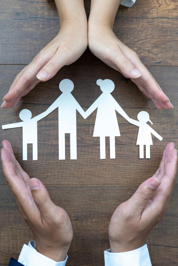 Hands protecting a paper cutout of a family